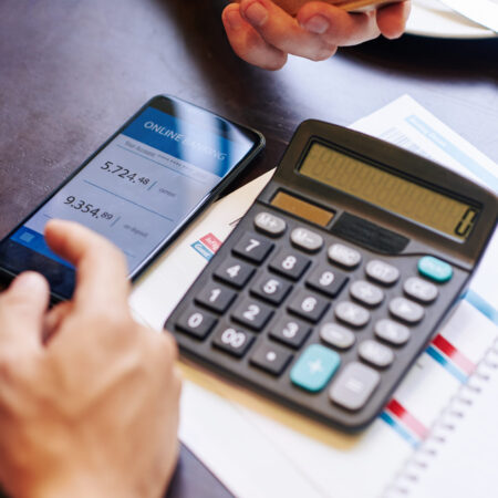 Close-up image of man checking his banking account via mobile application when calculating price of trip