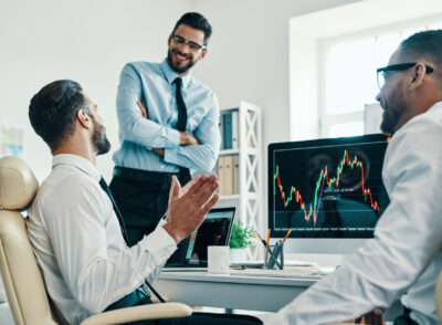 Working with investments. Group of young modern men in formalwear analyzing stock market data while working in the office